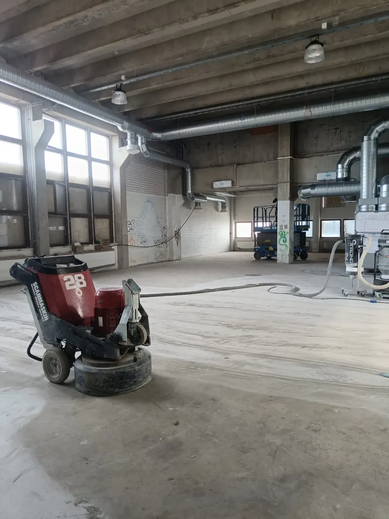 Betonilattian hiomakone ja pölynpoistoletku sisätyömaalla