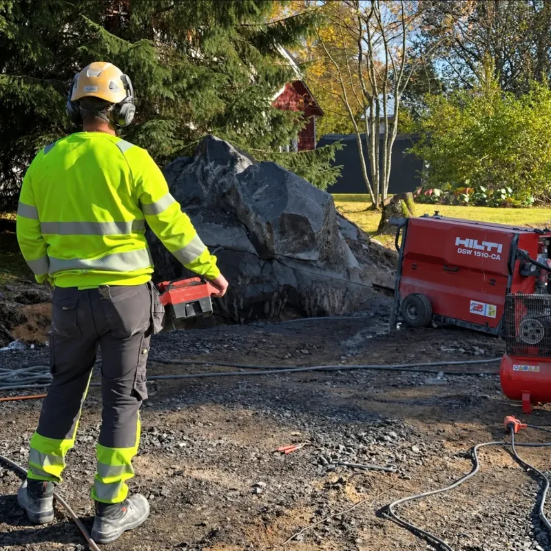 Työntekijä käyttää vaijerisahaa suuren kiven sahaamiseen